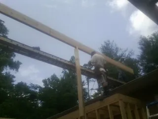 Carpenter setting a ridge beam over a new addition frame — Ice Dam Removal by Roofing Brothers in Meadow