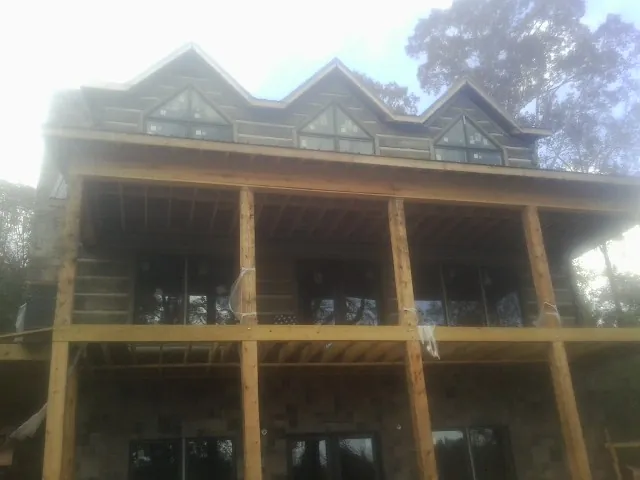 Dormers and porch framing on a large log home under construction — Roof Coating work by our crew in Meadow