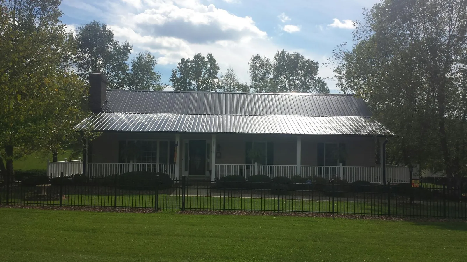 Gray metal roof on a brick ranch with a full width front porch — Gutter Guard Installation work by our crew in Meadow