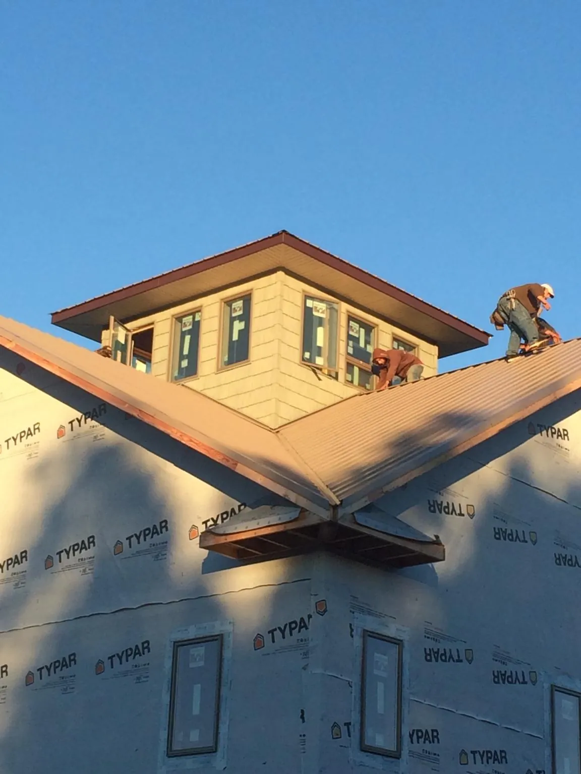 Roofers working around a rooftop cupola on a new metal roof at sunset — Roof Waterproofing in Meadow by Roofing Brothers